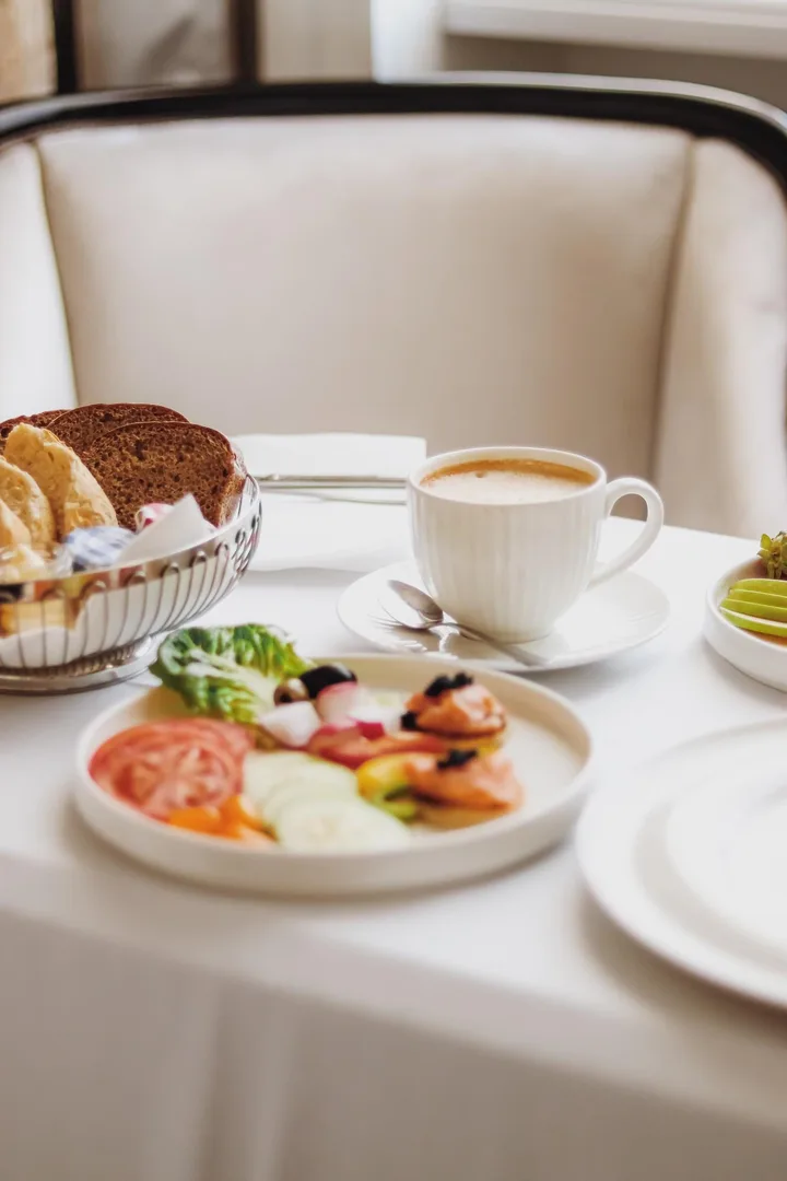 Petit-déjeuner servi à table avec café, pain, viennoiseries, fruits et assiette salée